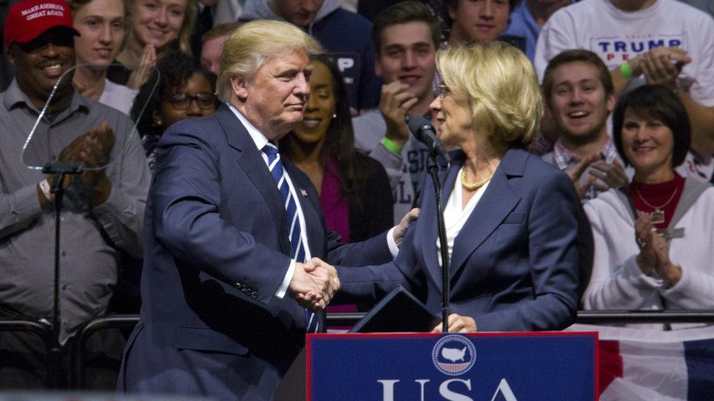 President-elect Donald J. Trump greets Betsy DeVos, his choice for education secretary, during his "USA Thank You Tour" at the DeltaPlex in Walker, Mich., Friday, Dec. 9, 2016. (Cory Morse/The Grand Rapids Press-MLive.com via AP)