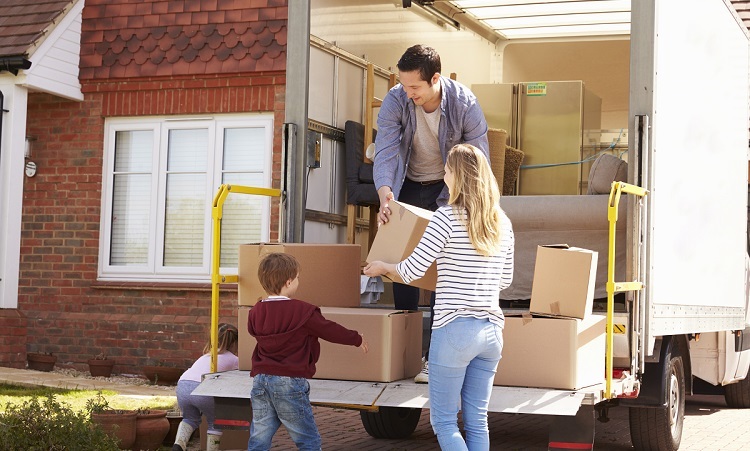 Family Unpacking Moving In Boxes From Removal Truck