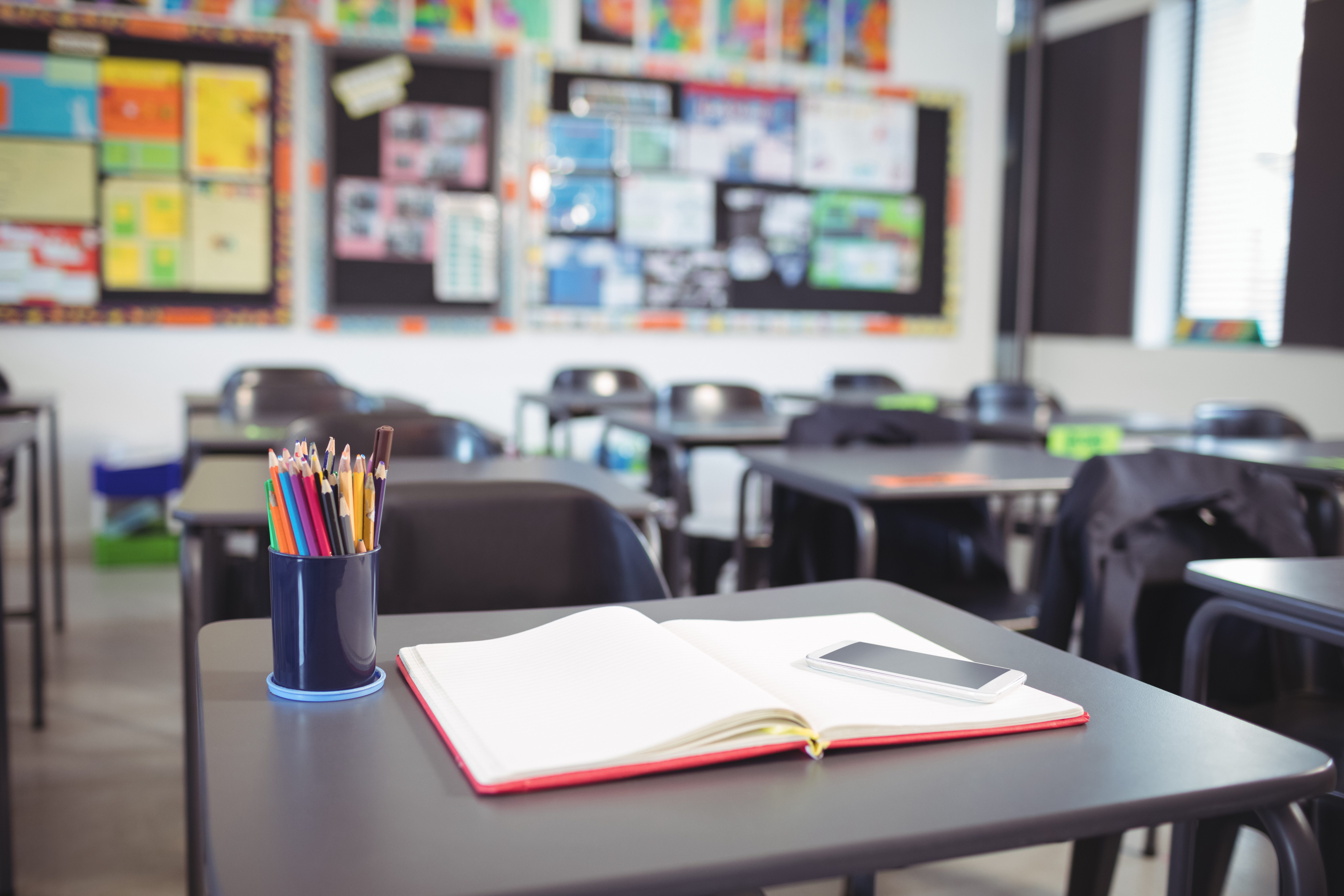 Mobile phone on open book at desk in classroom