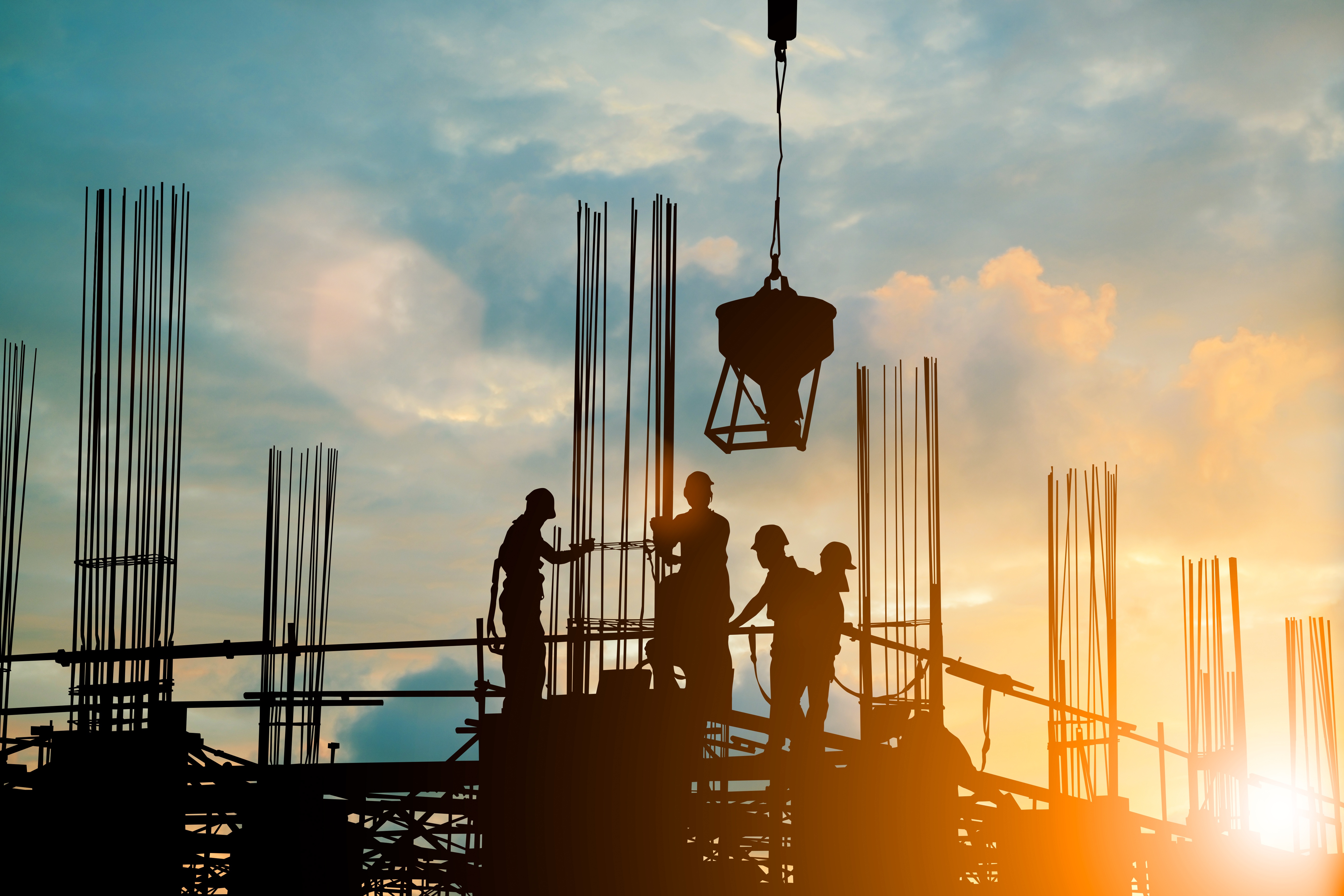 Silhouette of engineer and construction team working safely work load concrete on scaffolding on high rise building. over blurred background sunset pastel for industry background with Light fair