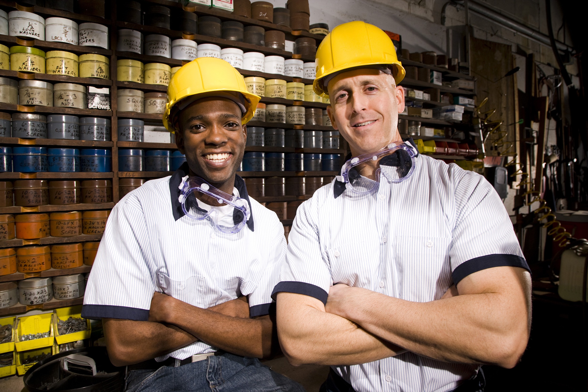 Male coworkers by shelves of colored inks in print shop