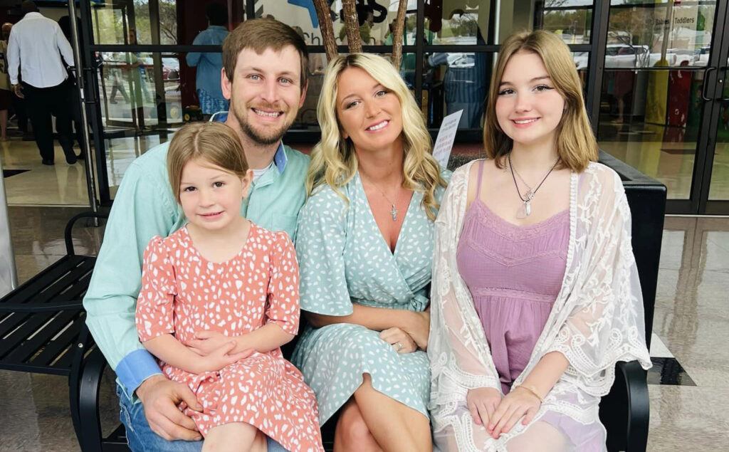 A family of four sitting together, two parents and two daughters